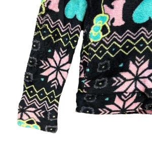 May include: Black fleece jacket with a colorful pattern of pink, blue, and green snowflakes, hearts, and geometric shapes.