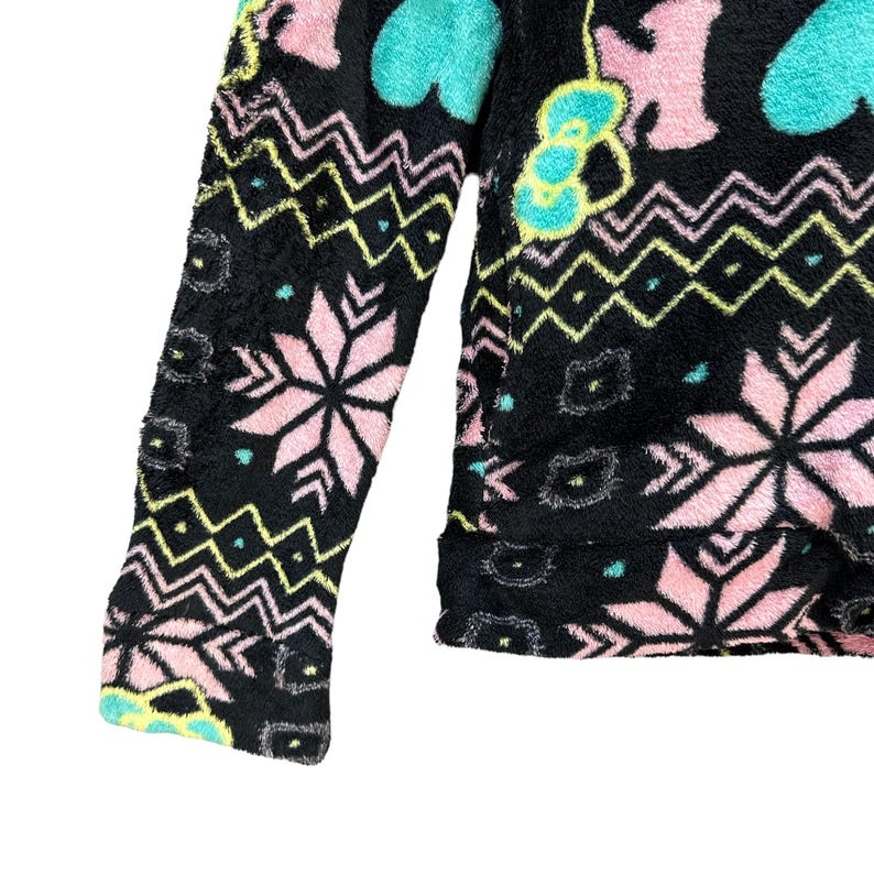 May include: Black fleece jacket with a colorful pattern of pink, blue, and green snowflakes, hearts, and geometric shapes.