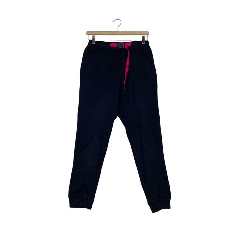 May include: Black sweatpants with a pink drawstring and a black belt.
