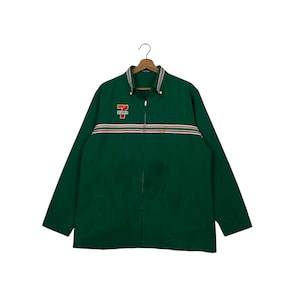 Puede incluir: Chaqueta verde oscuro con cremallera y mangas largas. La chaqueta presenta un pequeño logotipo en el pecho izquierdo y un diseño de rayas horizontales en el pecho. La chaqueta tiene cuello y dos bolsillos.