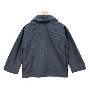 Puede incluir: Una chaqueta de color gris oscuro con rayas finas y cuello y mangas largas.