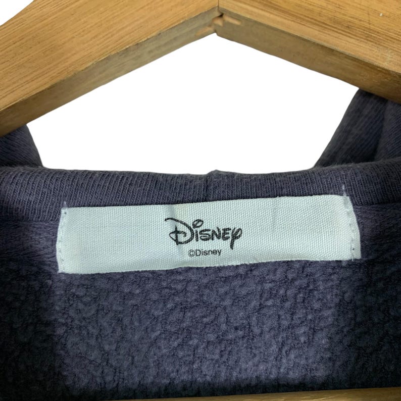 May include: A close-up of a dark blue hooded sweatshirt with a white tag that reads "Disney" and "&copy;Disney".