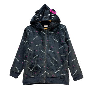 Może przedstawiać: Czarna bluza z kapturem zapinana na zamek z motywem Hello Kitty. Bluza posiada kaptur w kształcie głowy Hello Kitty, z uszami i r&oacute;żową kokardą. Materiał pokryty jest powtarzającym się tekstem "Hello Kitty" i r&oacute;żowymi akcentami kokard.