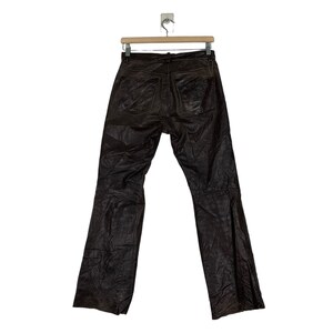 May include: Brown leather pants with a straight leg and a slight flare at the bottom. The pants have a zipper fly and belt loops.