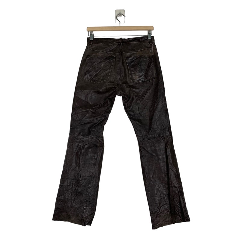May include: Brown leather pants with a straight leg and a slight flare at the bottom. The pants have a zipper fly and belt loops.