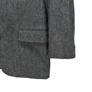 Puede incluir: Una chaqueta gris oscura con un solo bot&oacute;n de cierre y un bolsillo en el lado izquierdo. La chaqueta tiene una tela texturizada y un brillo sutil.