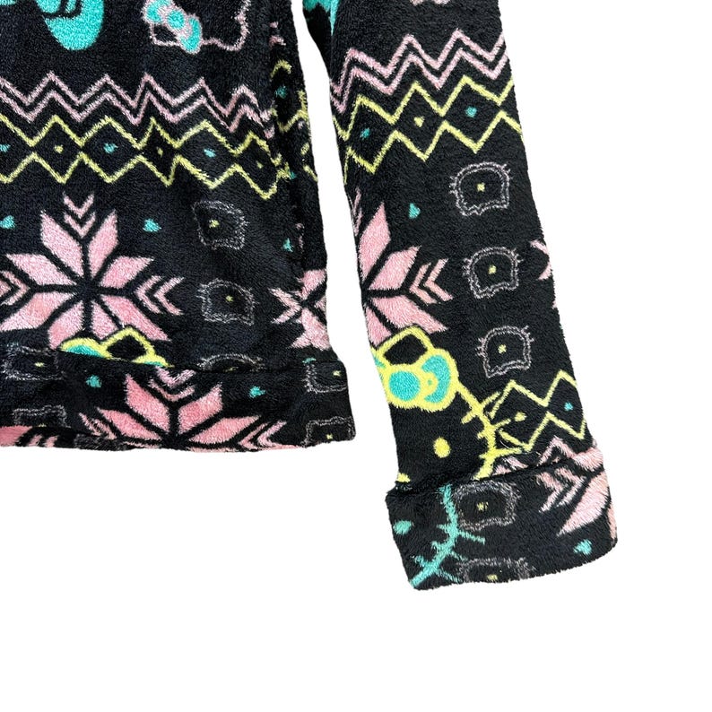 May include: Black fleece jacket with a colorful geometric and snowflake pattern. The jacket has a zipper closure and long sleeves.