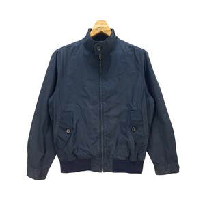 May include: A dark blue zip-up jacket with a stand-up collar and a ribbed waistband.