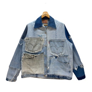 May include: A blue denim jacket with multiple patches and distressed details. The jacket has a button-up front and long sleeves.