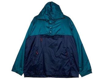 May include: Teal and navy blue anorak jacket with a hood and a front pocket. The jacket has a button-up closure and red zipper details. The Columbia logo is visible on the front. This vintage jacket is a stylish outerwear option.
