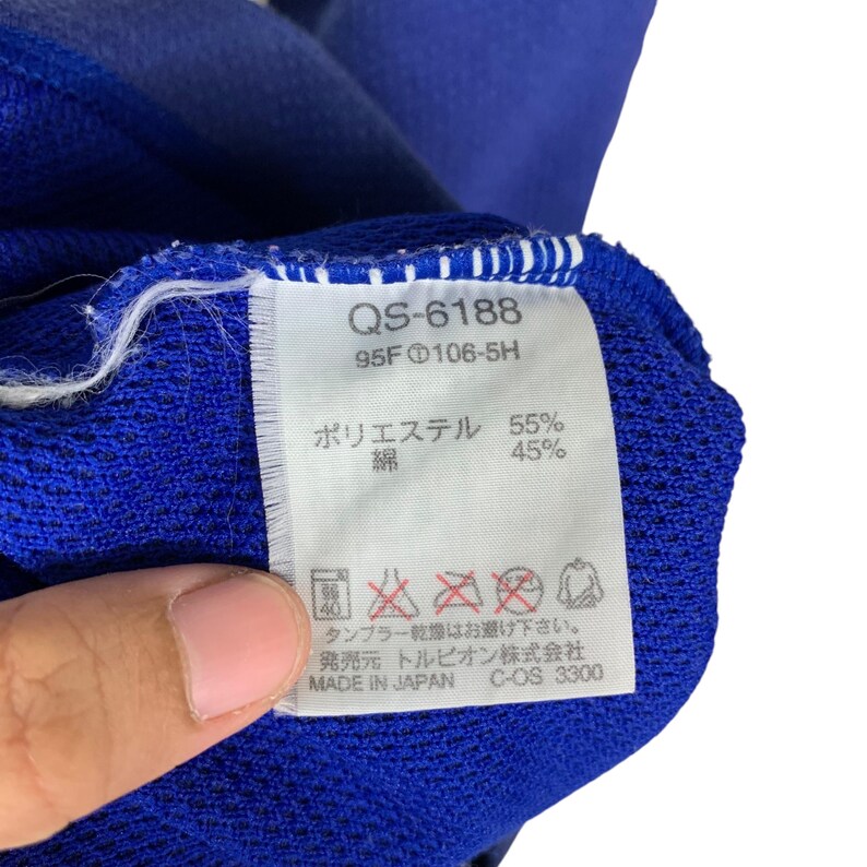Puede incluir: Una etiqueta de tela azul y blanca con el texto "QS-6188 95F 106-5H" y "Poli&eacute;ster 55% Algod&oacute;n 45%". La etiqueta tambi&eacute;n incluye instrucciones de lavado y cuidado en japon&eacute;s.