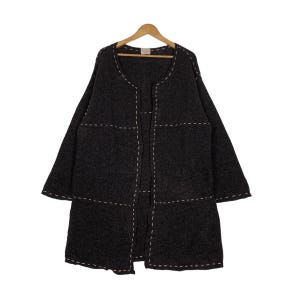 May include: A dark gray cardigan with a long, open front and long sleeves. The cardigan has a stitched design with white thread, creating a grid pattern.