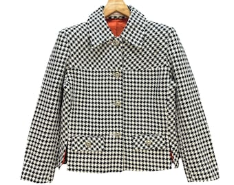 May include: A black and white houndstooth patterned jacket with a button closure and two pockets. The jacket has a red lining.