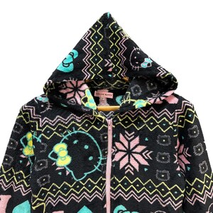 May include: Black fleece zip-up hoodie with a pink, blue, and green Hello Kitty pattern. The hoodie has a large Hello Kitty face on the front and a pink zipper.