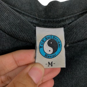 May include: A black T-shirt with a white tag that says "T & C Surf Designs Hawaii" and a yin yang symbol in a blue circle. The tag also says "M" for size.