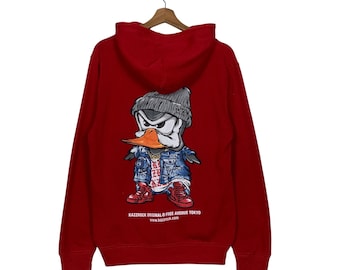 May include: A red hooded sweatshirt featuring a cartoon duck wearing a beanie, denim jacket, and red sneakers. The duck has an orange beak and a gold chain. The text "KAZZROCK ORIGINAL © FREE AVENUE TOKYO" is printed at the bottom.