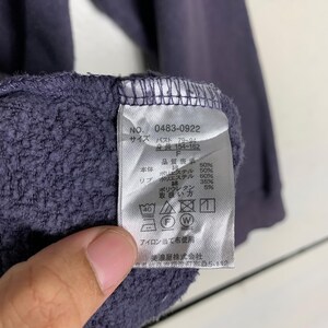 May include: A purple sweatshirt with a white tag that includes the text "NO. 0483-0922", "Size", "Bust 79-04", "154-162", "F", "Quality Display", "Main Body", "Polyester 50%", "Rib", "Polyester 60%", "Polyurethane 5%", "Handling", "Iron with a cloth", "Minoya Co., Ltd.", and "12".