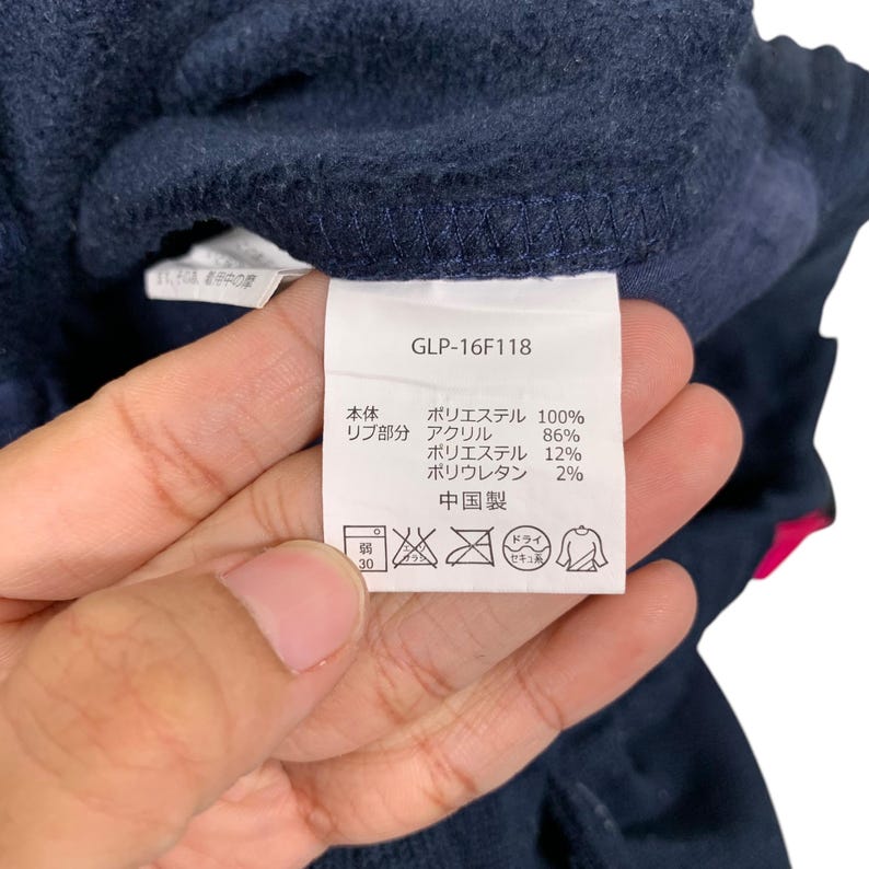 May include: A navy blue garment care label with white text and symbols. The label includes the text "GLP-16F118" and details the fabric composition: 100% polyester for the main body and 86% acrylic, 12% polyester, and 2% polyurethane for the ribbed portion. The label also indicates "Made in China".