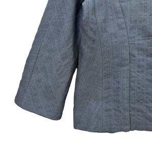 Puede incluir: Una chaqueta azul con un patr&oacute;n de rayas finas. La chaqueta tiene manga larga y un cierre de un solo bot&oacute;n.