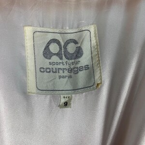 May include: White label with black text that reads "sport futur courr&egrave;ges paris" and a black "ac" logo. The label has a white border and is attached to a white fabric.