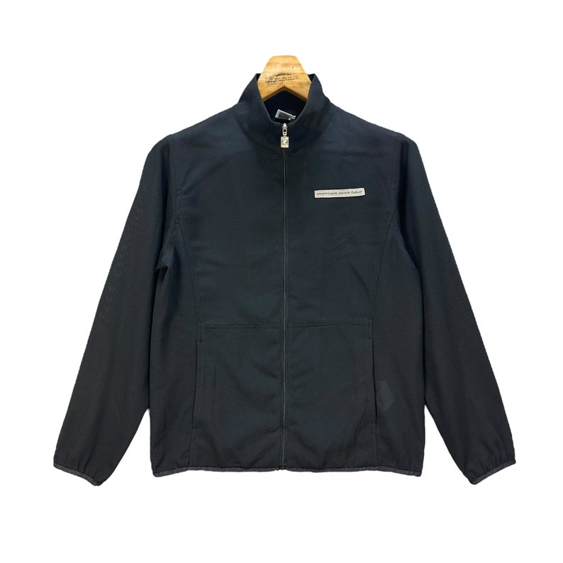 May include: A black zippered jacket with a small white label that reads "adventure starts here" on the left chest.