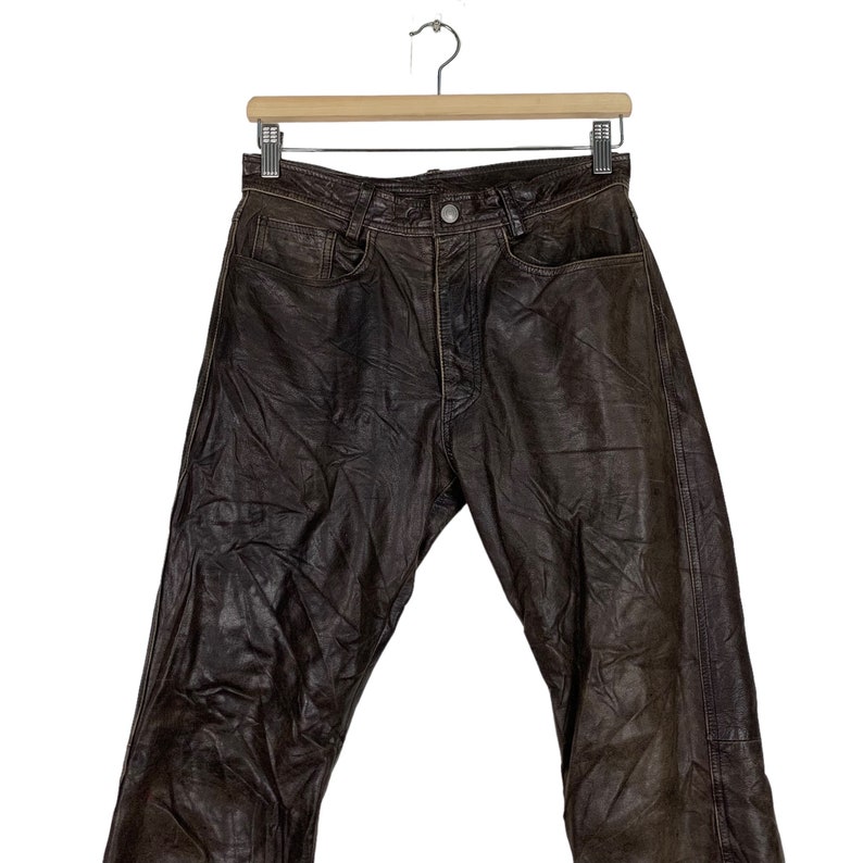 May include: Brown leather pants with a classic five-pocket design. The pants have a straight leg and a relaxed fit.