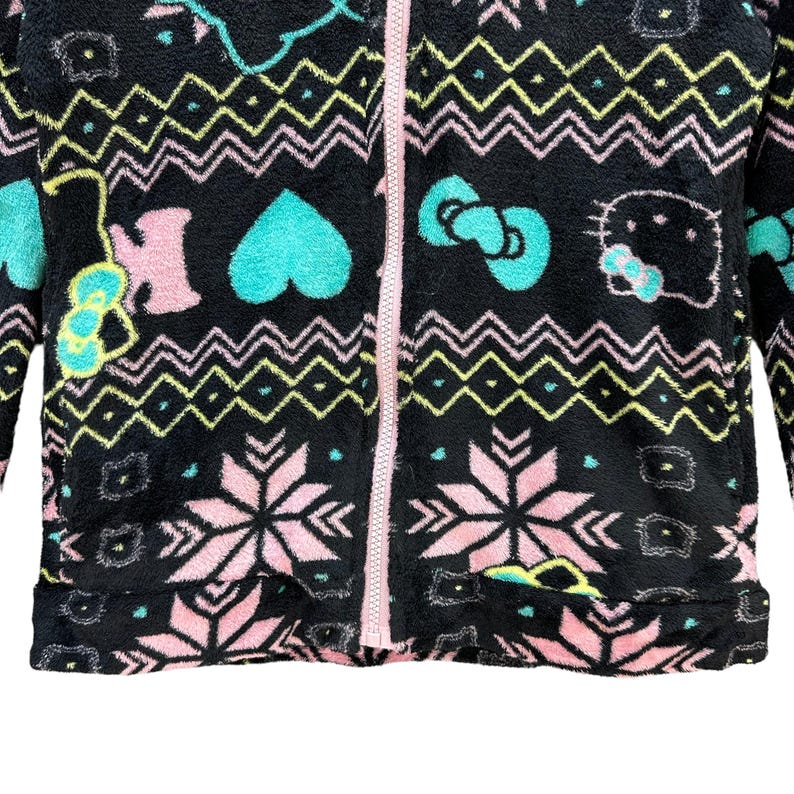 May include: Black fleece zip-up jacket with a pink, green, and blue patterned design featuring a Hello Kitty character.