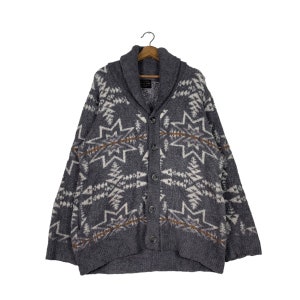 May include: A grey cardigan with a white and brown geometric pattern. The cardigan has a shawl collar and a button closure.