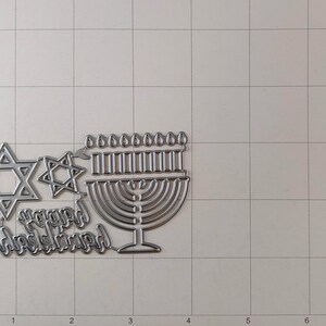 May include: Metal die cuts for scrapbooking or card making. The set includes a menorah, two Star of David designs, and the words "Happy Hanukkah".