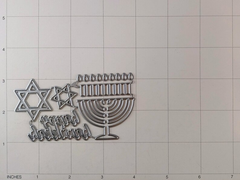 May include: Metal die cuts for scrapbooking or card making. The set includes a menorah, two Star of David designs, and the words "Happy Hanukkah".