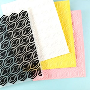May include: Four sheets of embossed paper with a hexagonal pattern. The sheets are in black, white, yellow, and pink.