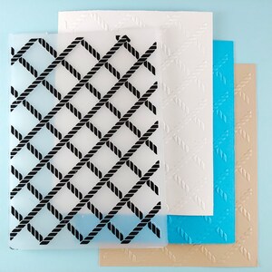 May include: Four sheets of clear plastic with a rope pattern. The top sheet has a black rope pattern, the second sheet has a white rope pattern, the third sheet has a blue rope pattern, and the bottom sheet has a tan rope pattern.