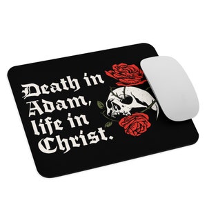 May include: Black mousepad with the text "Death in Adam, life in Christ." in white gothic font. A skull and red roses are on the right side. A white computer mouse is next to the mousepad.