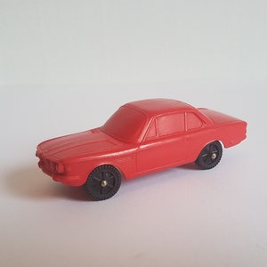 May include: A red toy car model of a classic BMW coupe. The car has black wheels and a detailed exterior.