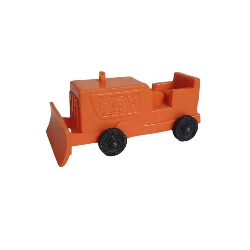 May include: Orange toy bulldozer with black wheels. The bulldozer has a blade in the front and a seat in the back. The toy is made of plastic and is a classic construction vehicle.