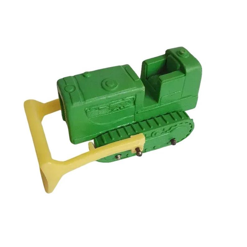 May include: Green toy bulldozer with a yellow blade. The bulldozer has a black track and a driver's seat.