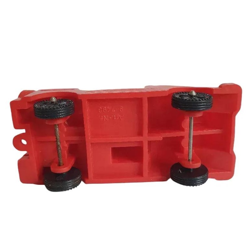 May include: A vintage red toy truck with black wheels and silver axles. The underside of the truck is visible, showing the wheels and the truck's structural details. The toy is made of plastic.