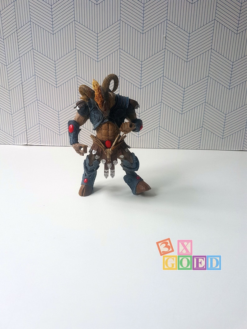 May include: A blue and brown plastic action figure of a horned warrior with red accents. The figure is standing on a white surface.