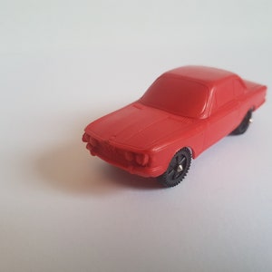May include: A red toy car model of a classic BMW.