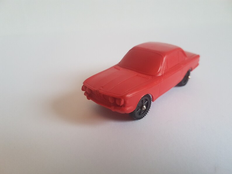 May include: A red toy car model of a classic BMW.