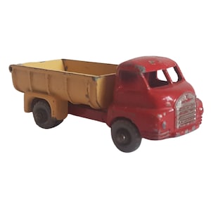 May include: A red toy dump truck with a yellow bed. The truck has a detailed cab and wheels.