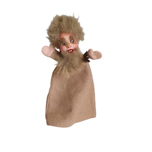 Peut inclure: Marionnette artisanale représentant un homme barbu avec des cheveux et une barbe bruns et touffus. La marionnette a un visage peint avec des joues roses et une bouche rouge. Le corps est en tissu beige et les bras sont petits et roses.
