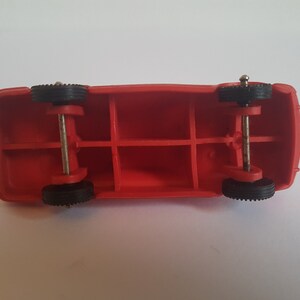 May include: Red toy truck with black wheels and a metal axle. The truck has a hollow body with four compartments.