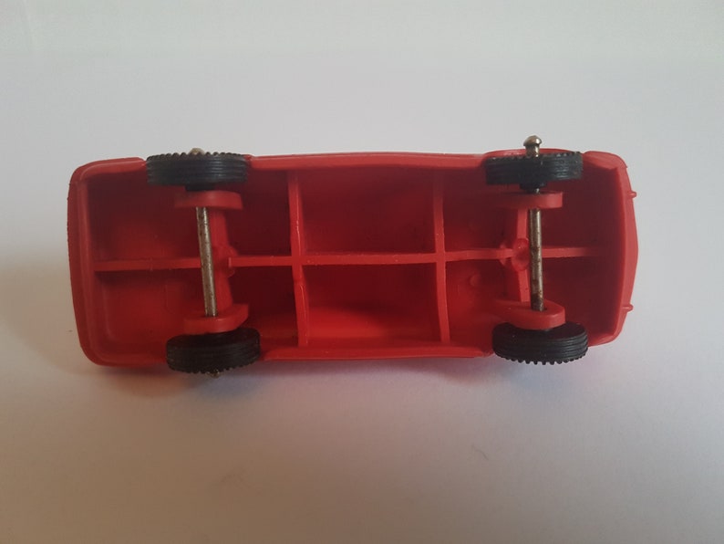 May include: Red toy truck with black wheels and a metal axle. The truck has a hollow body with four compartments.