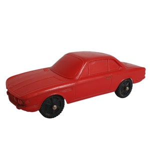 May include: A red toy car with black wheels. The car has a detailed design and is made of plastic.