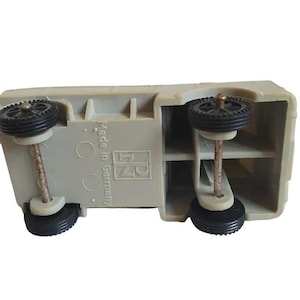May include: A gray toy truck with black wheels and the text "Made in Germany" and "RN" printed on the bottom.
