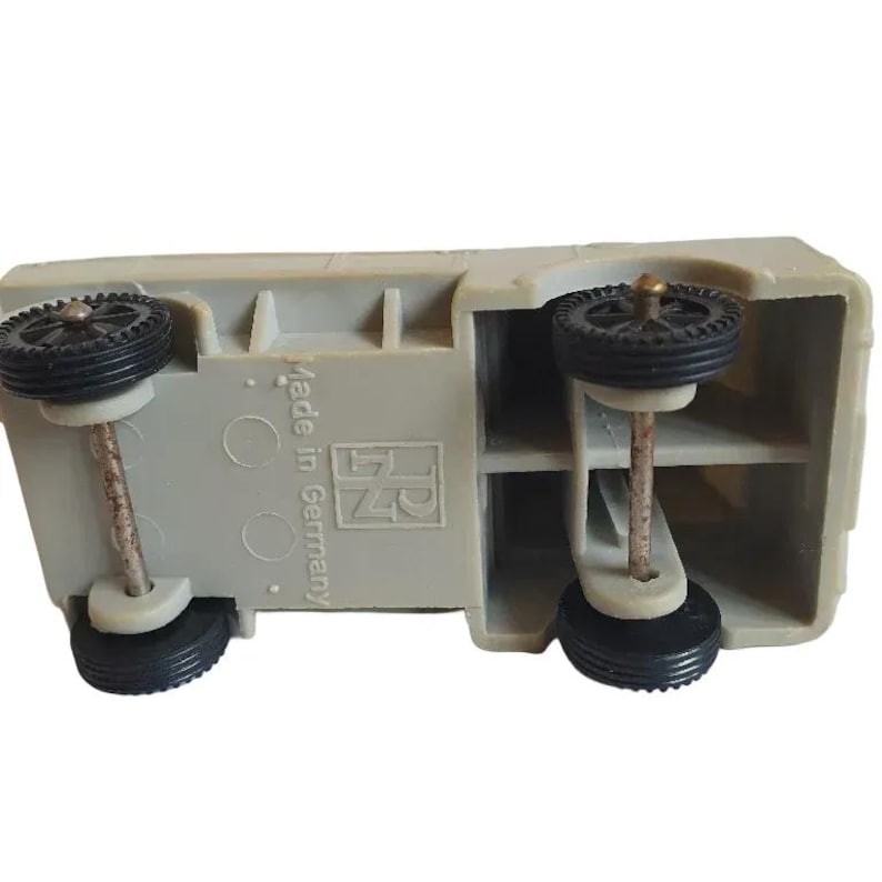 May include: A gray toy truck with black wheels and the text "Made in Germany" and "RN" printed on the bottom.