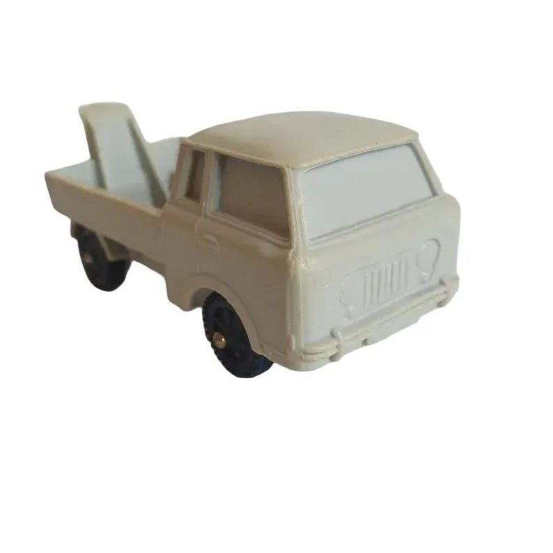 May include: A light gray toy truck with a flatbed and a cab. The truck has black wheels and a black grill.