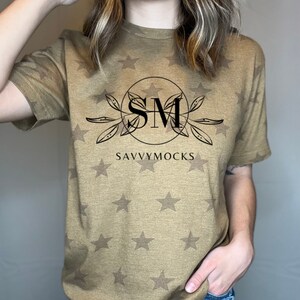 May include: A brown t-shirt with a white star pattern. The shirt has a black graphic with the letters "SM" in a circle and the text "SAVVYMOCKS" below.