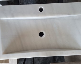 Pode incluir: Pia de banheiro de mármore branco com um design curvo e dois orifícios de drenagem.